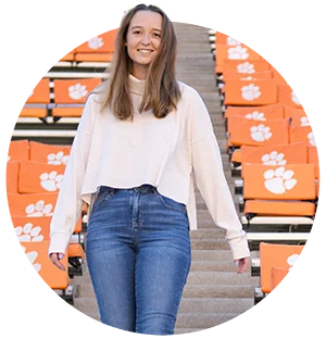 A female student walks down stairs between orange seating on both sides of her marked with the Clemson Tiger Paw logo.