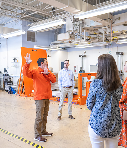 A Clemson professor and student explain the technology in their lab to a group.