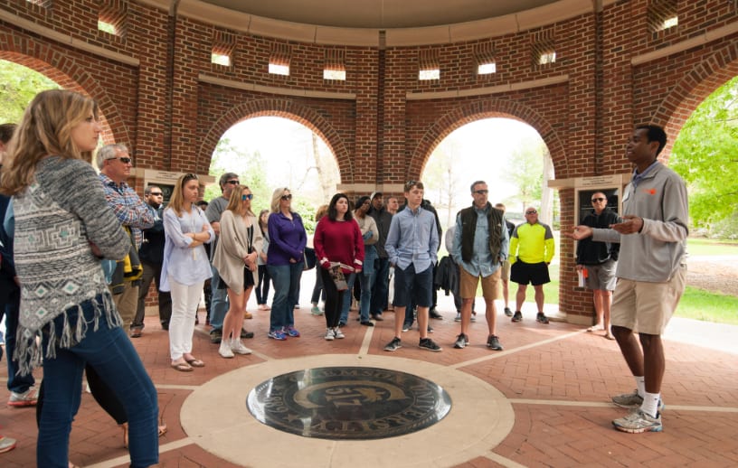 Student tour guide speaks to a tour group while standing under the President's Park Rotunda.