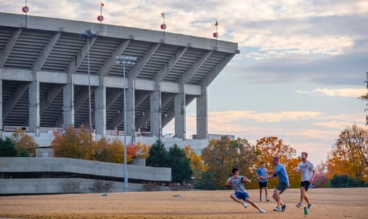 Four male Clemson students play touch football on an intramural field beside Memorial Stadium.