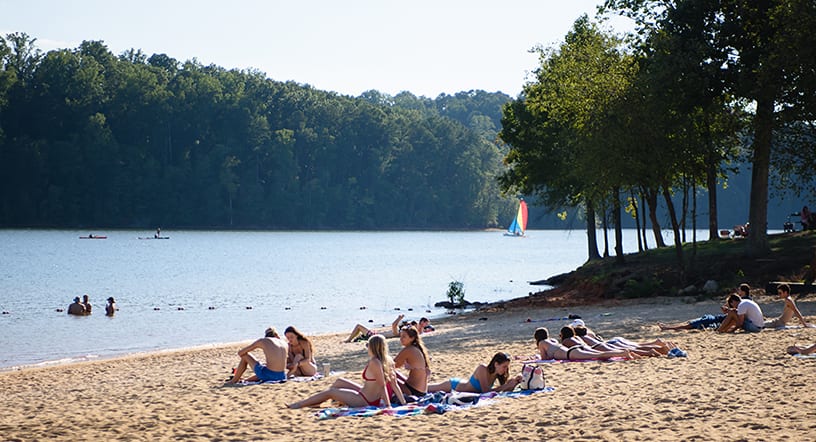 Clemson students relax in the sand beside Lake Hartwell, swim, kayak and sail in the lake