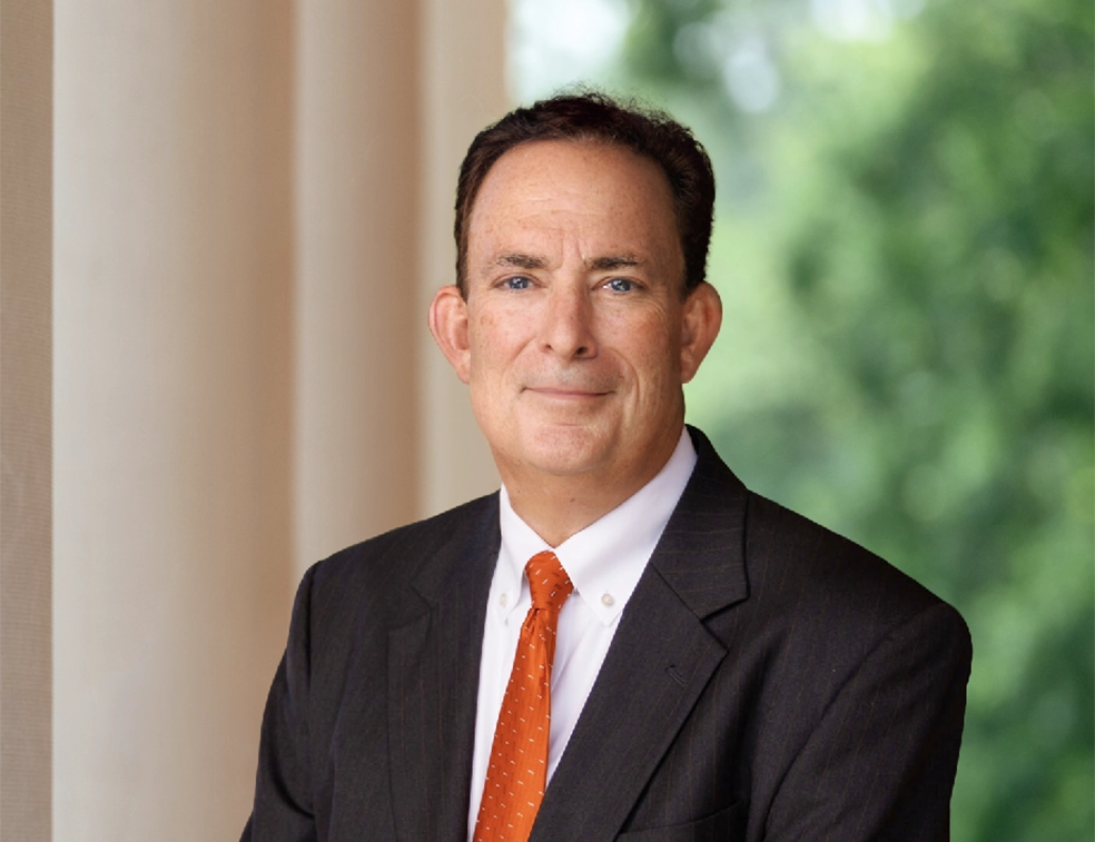 A smiling President-Elect Ayers in a dark suit with an orange tie.