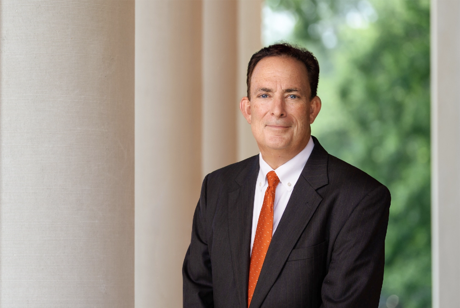 A smiling President-Elect Ayers in a dark suit with an orange tie.