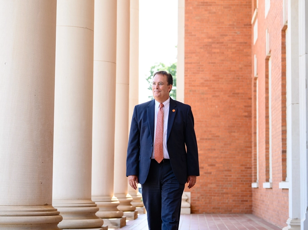 Clemson President Benjamin C Ayers walking near the entryway columns of Sikes Hall