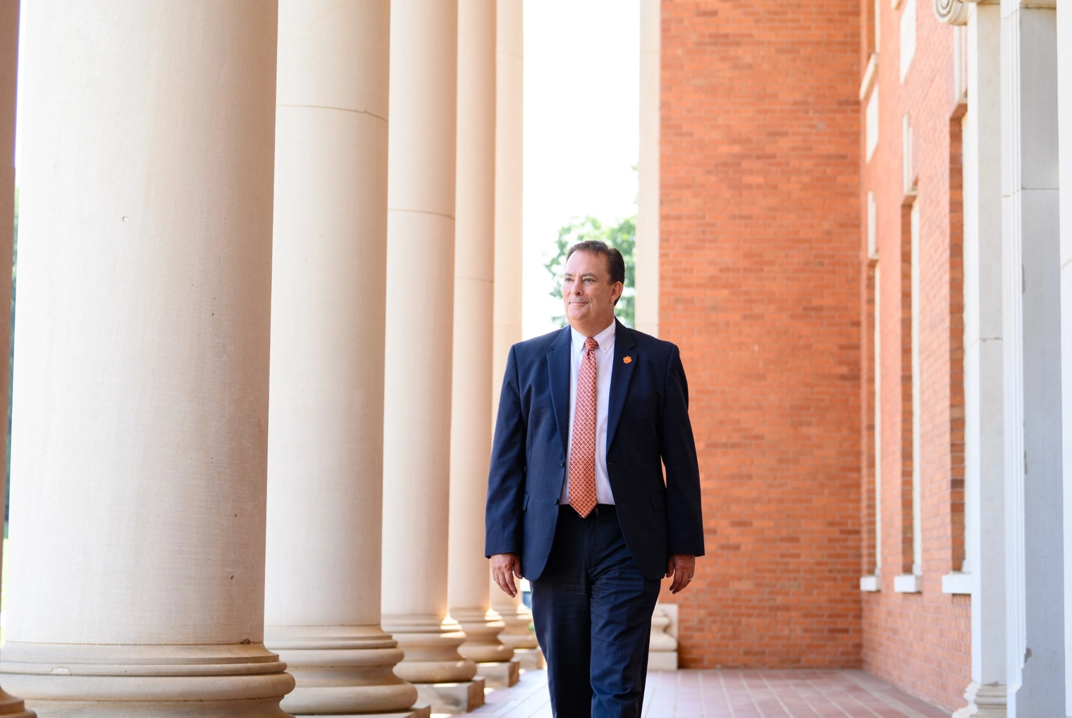 Clemson President Benjamin C Ayers walking near the entryway columns of Sikes Hall