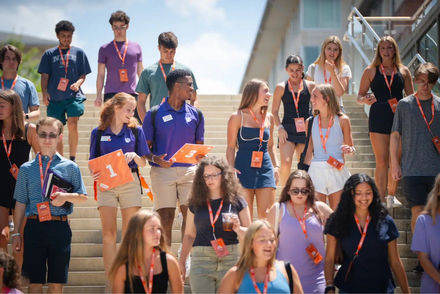 A crowd of first-year students wearing orange lanyards descend a set of stairs while attending orientation