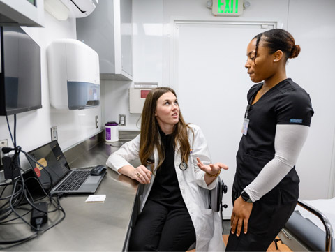 Caitlin Kickham consults with another health care professional in an exam room.