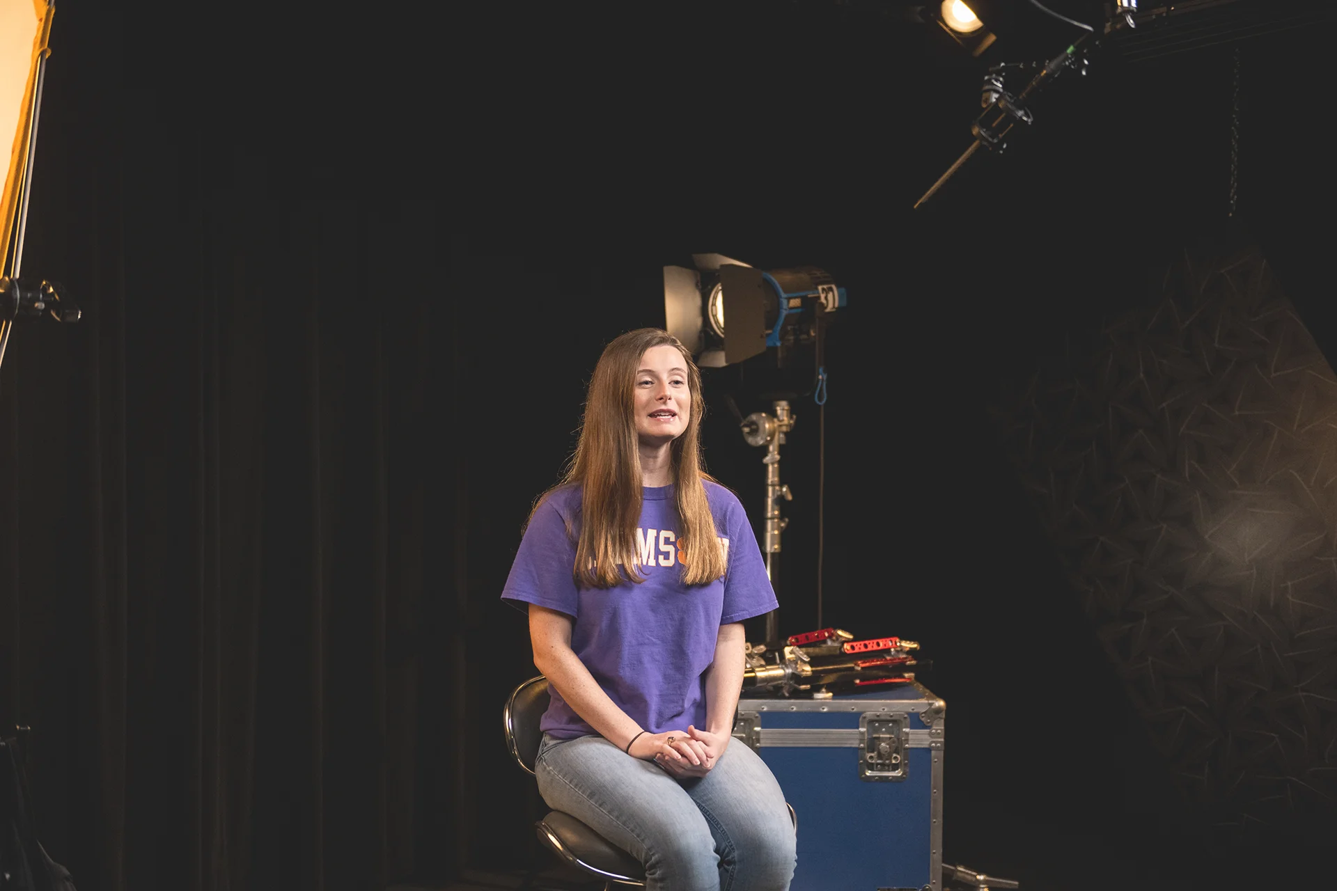 Preview image of student Erin Griffin, wearing a purple Clemson shirt and sitting in a studio. An arrow indicating a movie will play when clicked appears in the middle of the image.