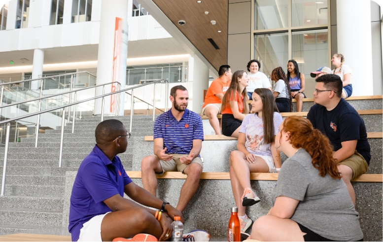Hunter Renfrow sits on some steps with a group of students while having a discussion with them.