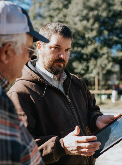 Kendall Kirk explains something to a farmer while showing him something on an tablet.