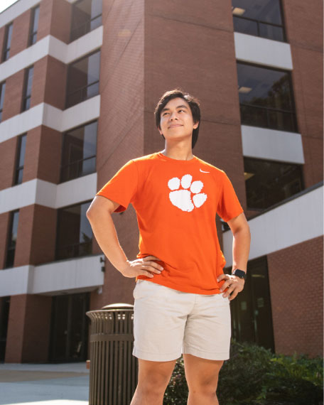 Edwards Hall, a five-story brick public health building is lit by bright sunlight on Clemson's campus.