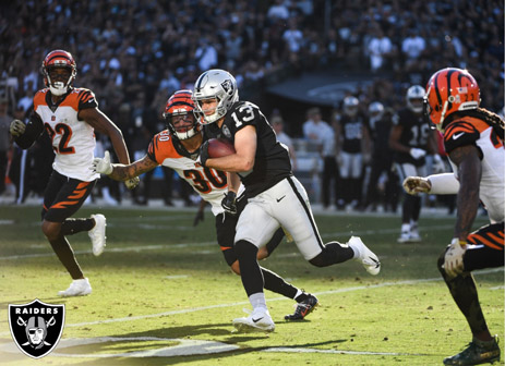 Hunter as a Las Vegas Raider running the ball after a reception while in the middle of several defenders.