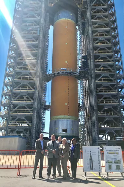 Vaness stands with a group in front of the Space Launch System rocket