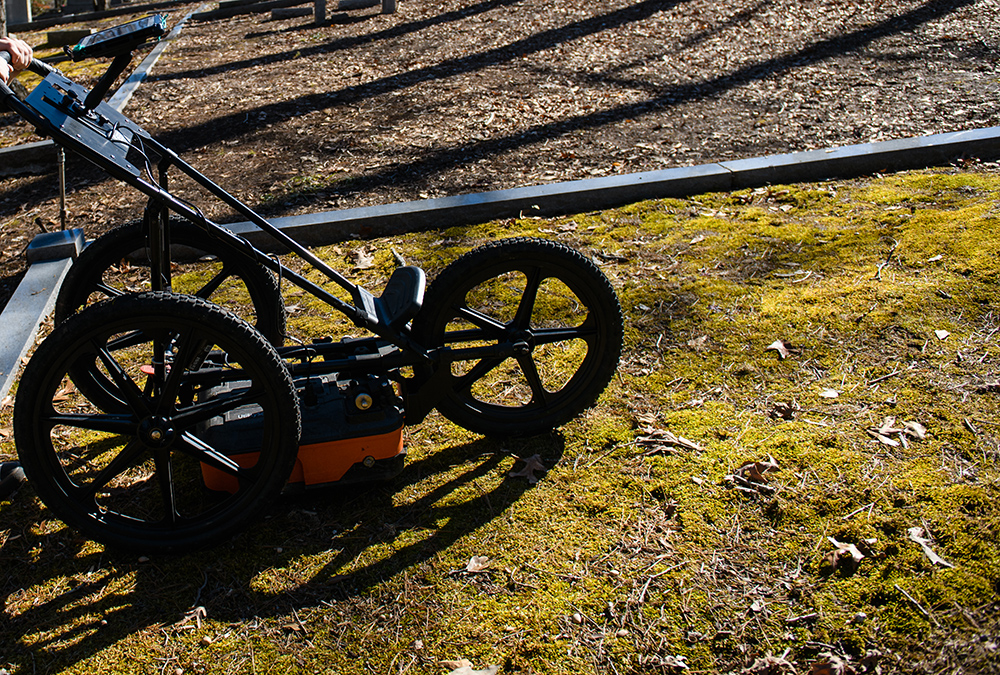 A technician pushes a GPR unit over the ground at Woodland Cemetery.