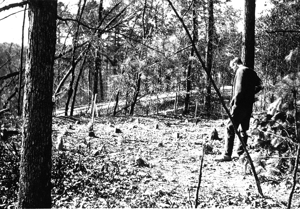 A man stands near fieldstones in Cemetery Hill, circa 1950s-1960.