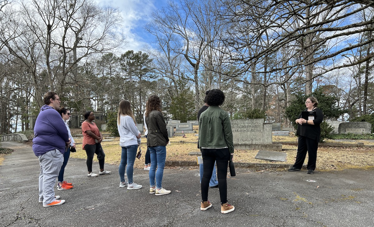 A group listening to a tour guide on the cemetery tour.