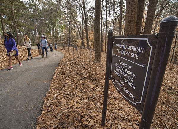 Tour participants walking in Woodland Cemetery near a sign designating the site.