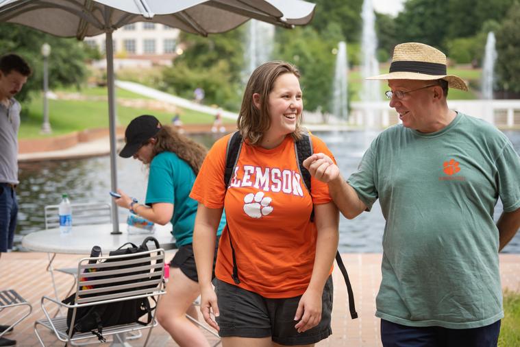 A female student walks alongside a faculty advisor by the reflection pond