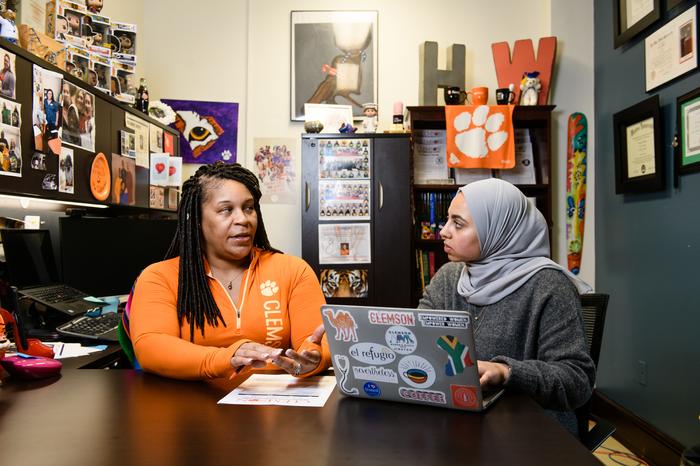 A female faculty advisor gives feedback to a female student inside her office. 