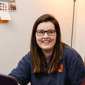 Abby Fleig wearing a purple Clemson sweatshirt while smiling.