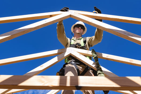 a construction science student in safety gear helps construct a truss for the habitat for humanity home