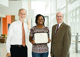 Bob Jones and John Griffin stand beside Candace holding a plaque.