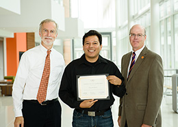 Bob Jones and John Griffin stand beside Jorge holding a plaque