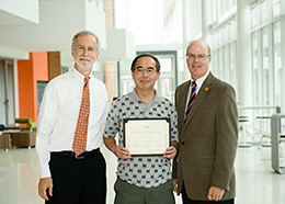 Bob Jones and John Griffin stand beside Lih-Sin holding a plaque