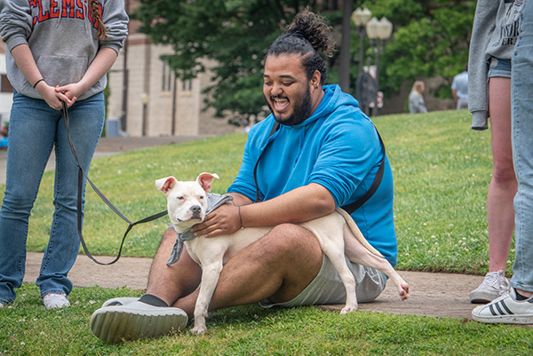 Excited students laughs while petting a puppy at the Rent a Puppy event