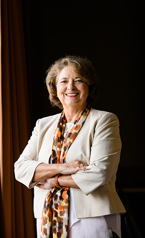 Kim Wilkerson in a khaki blazer and orange and brown infinity scarf.
