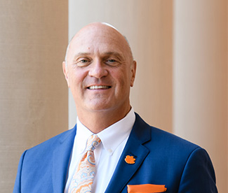 President Clements standing in front of the large columns at Sikes Hall.
