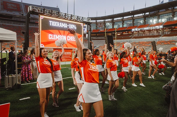 A large group of Clemson cheerleaders wave and smile at the cameras and crowd during Tigerama.