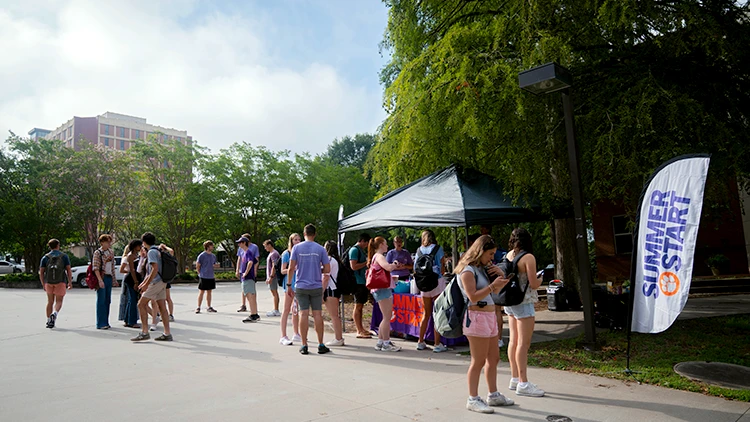 students stand outside a tent that reads Summer Start on their way to class