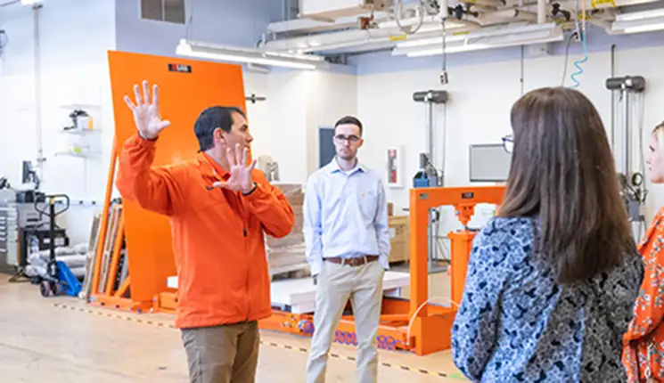 An instructor gestures to show guests equipment in an educational building.