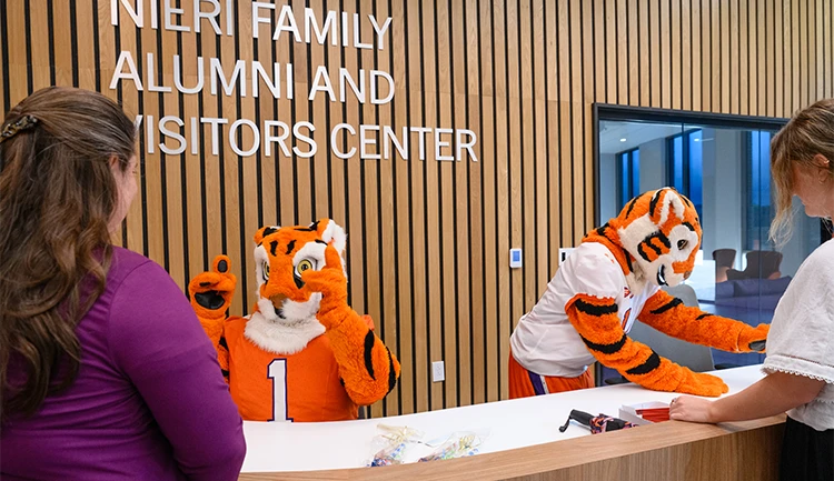 the tiger mascot and cub sit behind the reception desk at the visitors center talking to visitors