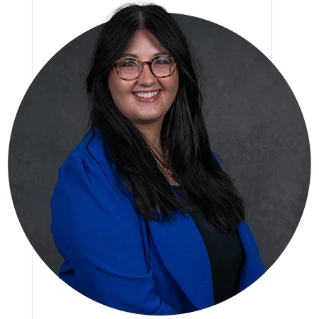 A female student wearing a royal blue blazer and glasses poses for a headshot.