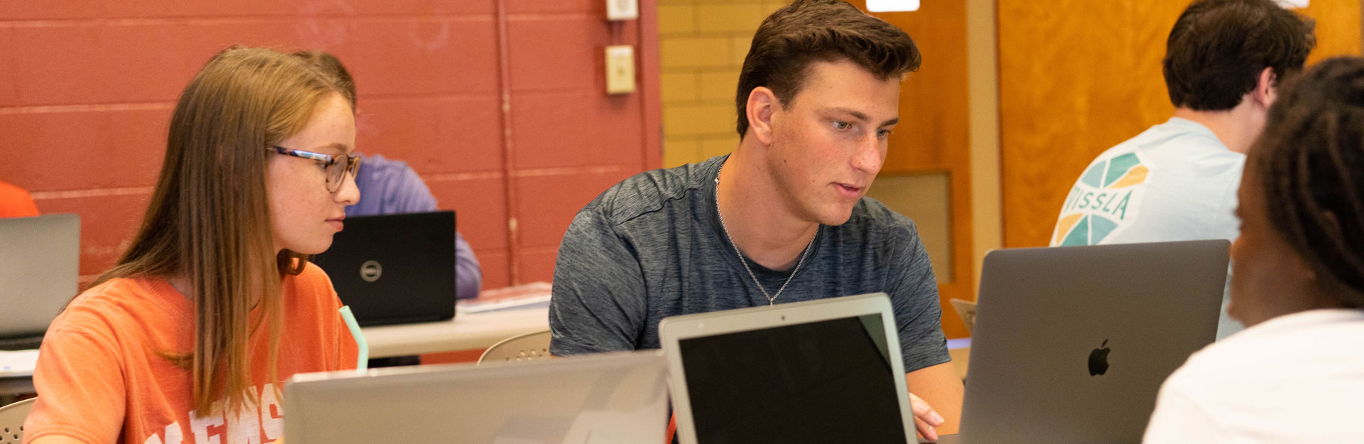 groups of students work on laptops in a Clemson classroom