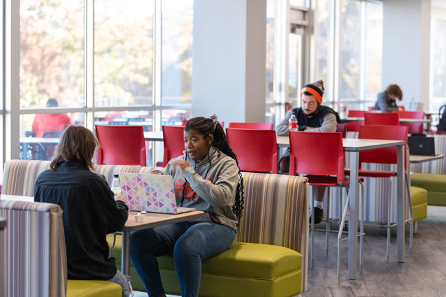 two female students sit across from each other at table inside a Tricounty's campus building