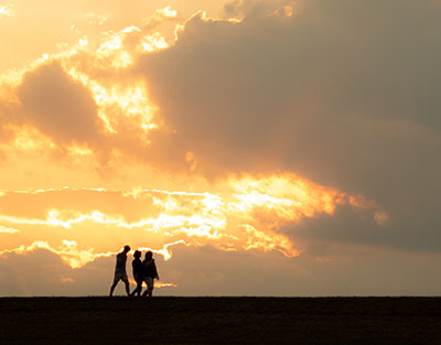 Silhouetted figures walking against a dramatic sunset filled with vibrant orange and yellow hues.