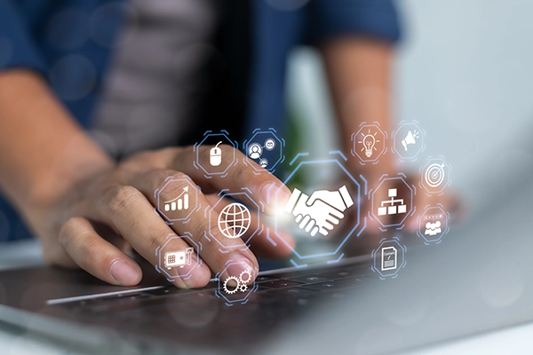 Close-up of hands using a laptop with floating digital icons, including a handshake, security lock, and analytics symbols.
