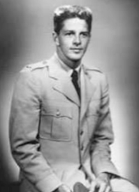 A black and white portrait of a young man in a military uniform, sitting and looking towards the camera.