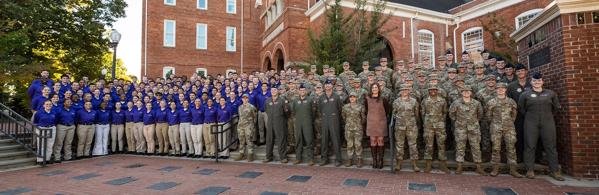 Group photo of male and female students in Air Force camouflage and uniforms standing in front of Tillman Hall.