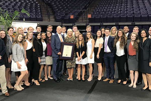 Large group of Chapman Scholars including Thomas F. Chapman and wife posing for photo and holding certificate in Littlejohn Coliseum.