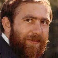 Portrait of a man with a full beard and a warm smile.