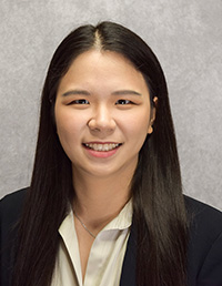 Professional headshot of a smiling woman with long dark hair, wearing a light-colored blouse.