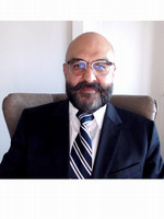 A smiling man with a beard wearing glasses and a formal suit and tie.
