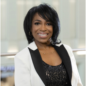 Professional portrait of a woman smiling, wearing a black and white blazer with sequins underneath.