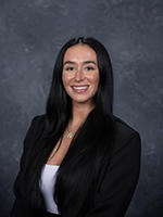 Professional headshot of a smiling woman with long black hair, wearing a black blazer and white top.
