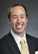 Smiling professional headshot of a man in a suit and tie.