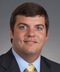 Professional headshot of a man in a suit and tie, with a friendly expression.